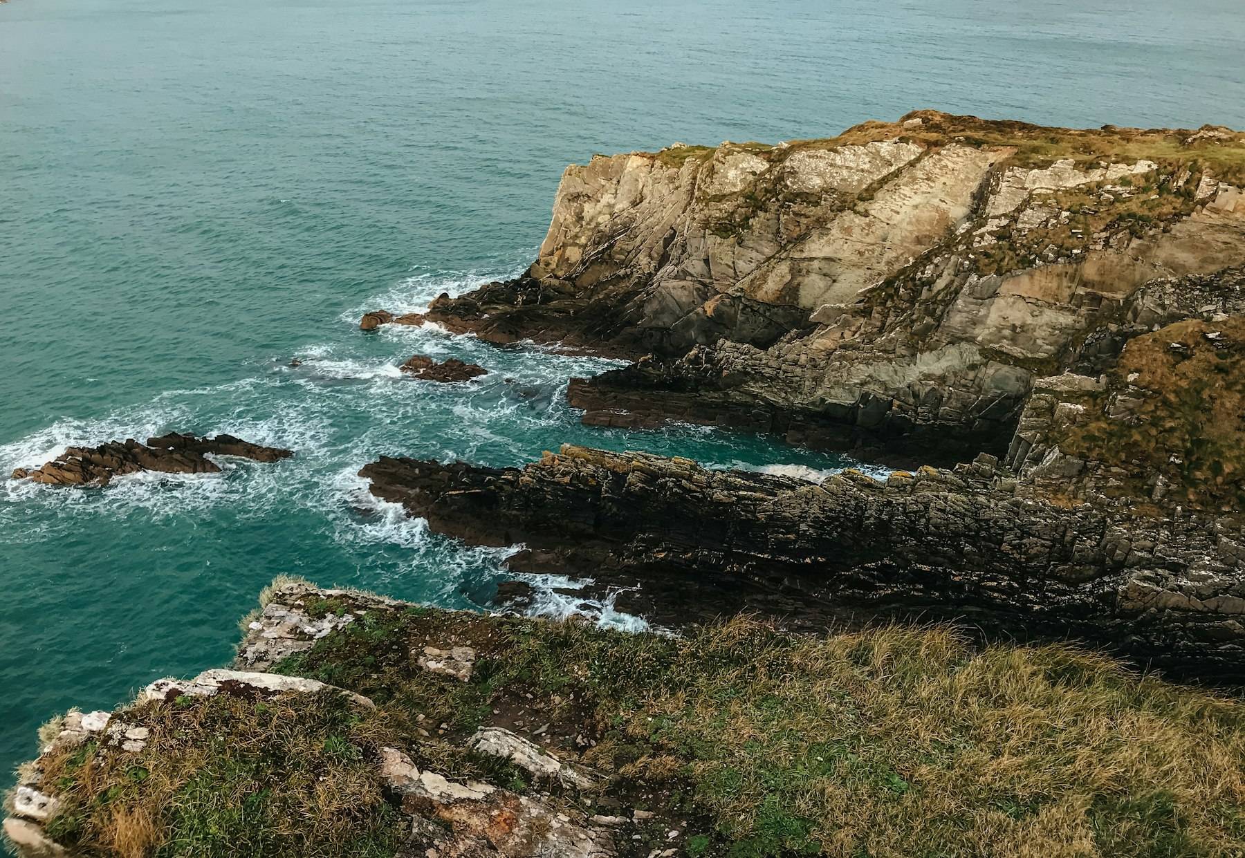 Rugged green clifftop above the turquoise sea on the Irish coast