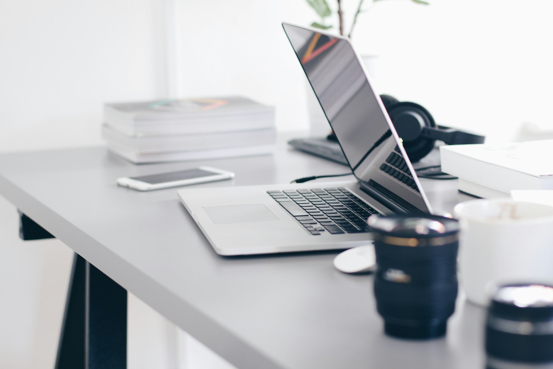 Laptop on a white desk with documents and a coffee cup