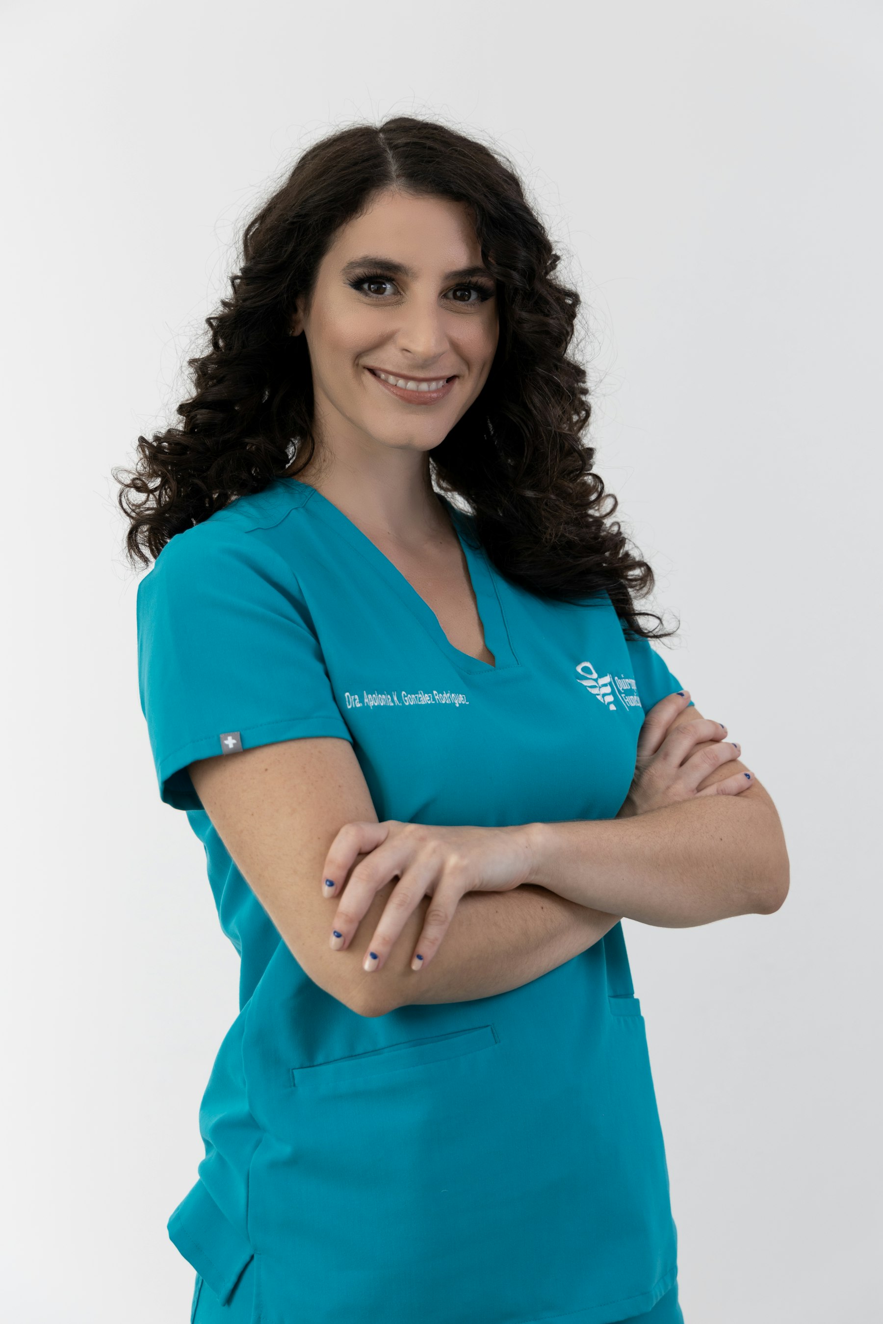 Smiling nurse in teal scrubs standing with arms folded
